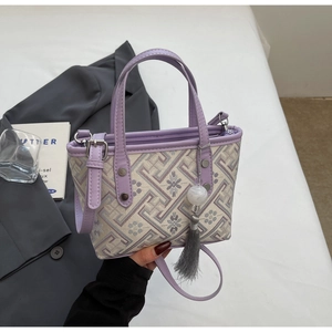 Detail of beige and purple jacquard bucket bag with tassel and leather handle