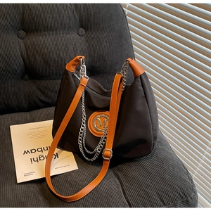 Close-up of the large nylon dumpling bag featuring a metal M logo and silver chain detail