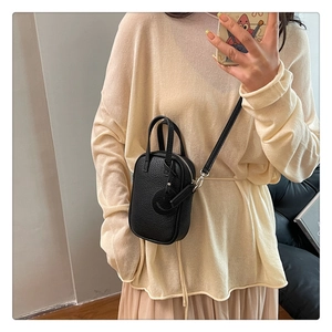 Mirror selfie showing a black pebble leather crossbody bag with a smiley face charm