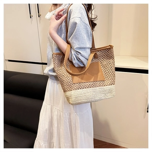 Detail of color-blocked straw tote bag with brown leather patch and shoulder straps