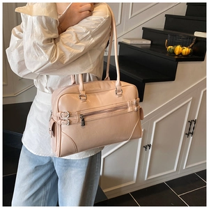 Close-up of pink Boston handbag with dual straps and silver hardware detail in indoor setting