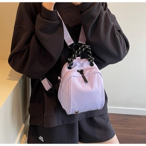 Close-up of lavender nylon shell bag with braided handle shown on a model