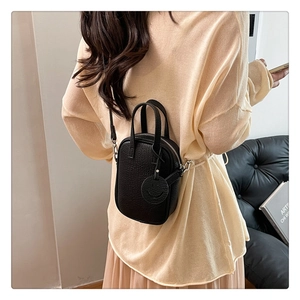Black litchi grain mini handbag with smiley charm shown on model in home setting
