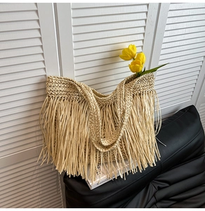 Gros plan d'un sac cabas en paille avec de longues franges décoratives et une anse ronde