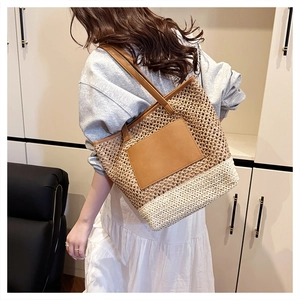 Detail of two-tone woven tote bag with brown faux leather handles and patch in home setting