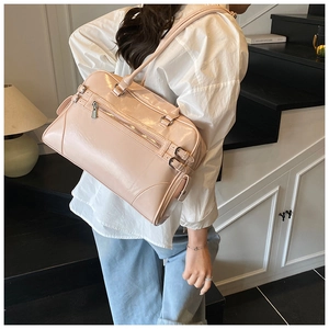 Polished pink leather Boston bag shown on shoulder with stylish metallic buckle details