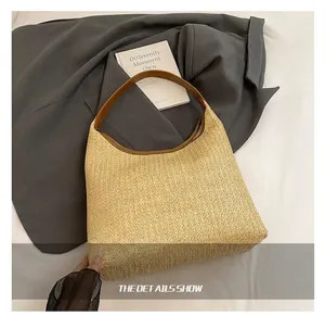 Detailed overhead shot showing the woven straw texture and leather strap of the large beach bag