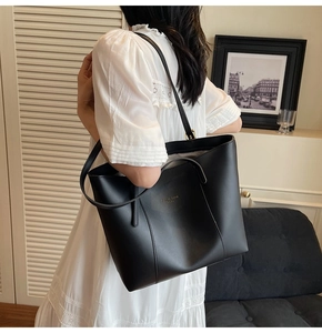 Détail d'un grand sac cabas noir en cuir avec lettrage doré et bandoulière élégante