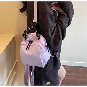Close-up of purple nylon mini backpack with a woven black and white rope handle on a model