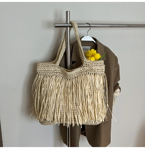 Détail d'un grand sac cabas de plage en paille avec de longues franges tressées