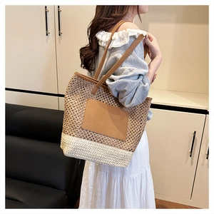 Close-up of woven straw tote bag with brown leather handles and two-tone texture