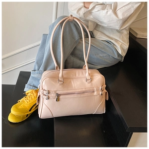 Detail view of light pink Boston bag with metallic buckles and sleek surface texture