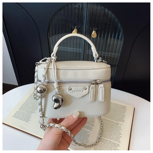 Detail der cremeweißen Mini-Box-Tasche mit Herzanhänger und silberner Kette