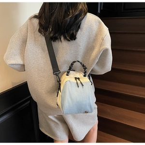 Rear view of a model carrying a light blue denim and cream canvas shell backpack on stairs