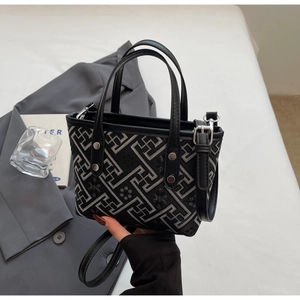 Close-up of black bucket bag with grey geometric patterns and silver hardware details