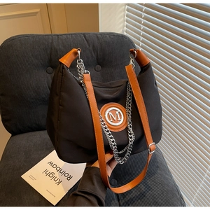 Detail of black nylon crossbody bag with silver M logo and brown leather handles