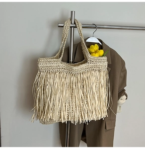 Gros plan du sac cabas en paille beige avec de longues franges et une texture tissée
