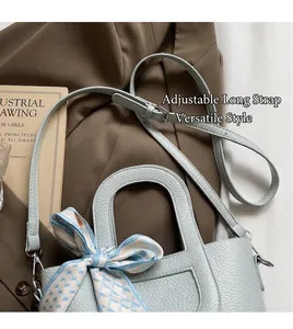 Dettaglio borsa in pelle azzurra con motivo litchi e foulard sopra un libro vintage