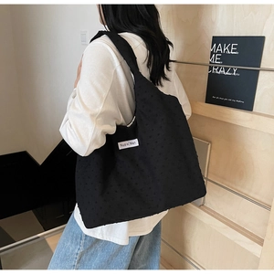 Detail view of black tote bag featuring unique 3D dotted texture and brand logo label