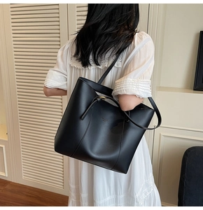 Vue de dos d'un grand sac cabas en cuir noir mat porté par un mannequin dans une pièce