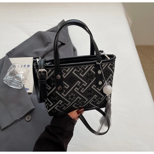 Detail of black embroidered bucket bag with grey geometric floral patterns and tassel
