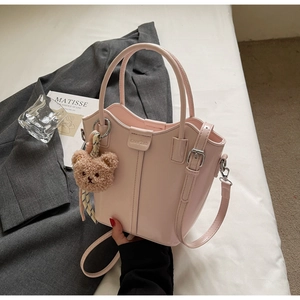 Detail shot of light pink leather bucket bag with cute brown teddy bear charm