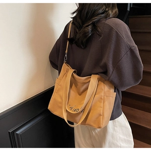 Detailed side view of khaki canvas tote bag showing functional pocket and strap