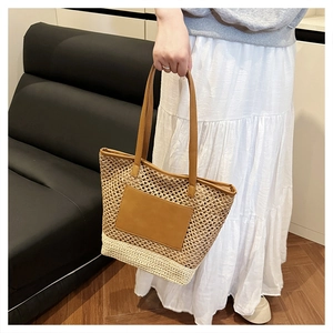 Detail of woven straw tote bag with brown leather handles and boho hollow grid texture
