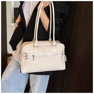 Detail view of cream white shoulder bag with glossy finish and decorative zippers