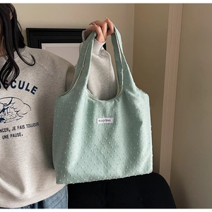 Detail of mint green tote bag featuring 3D flocked dots and a woven brand label