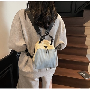 Detail of color-block mini denim backpack with woven rope handle and wide shoulder strap