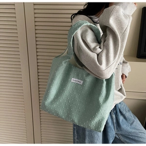 Detailed close-up of mint green canvas tote bag featuring textured 3D polka dot fabric