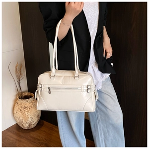 Detail shot of a cream Boston handbag with metal buckles and zippers in a retro office style