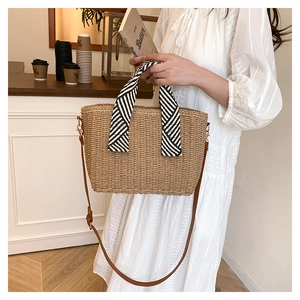 Détail du sac cabas en paille tissée avec poignées en soie rayées et bandoulière en cuir