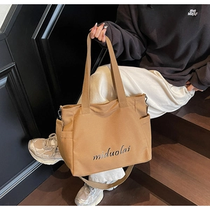 Detailed macro view of caramel canvas tote bag showing side pocket and printed logo strap