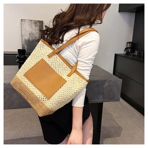 Detail of woven straw tote bag featuring a leather pocket and dual-tone texture
