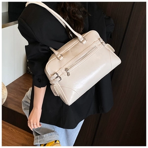 Detail view of cream leather Boston bag with side metal buckles on a person
