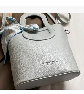 Dettaglio borsa a secchiello azzurra in pelle martellata con foulard di seta sul manico