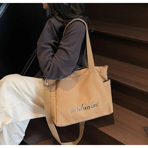 Detail of khaki canvas tote bag showing side pocket and adjustable shoulder strap