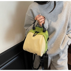 Side view of avocado green and beige waterproof nylon shell bag worn as a shoulder bag