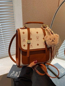 Brown leather vintage backpack with teddy bear print and plush charm on a book background