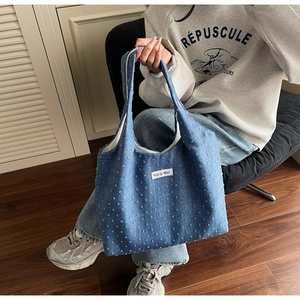 Detail of blue textured tote bag with brand patch and woven jacquard fabric finish