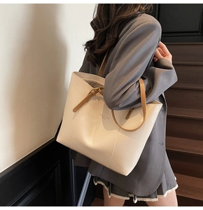 Détail du sac cabas minimaliste avec corps crème, anses en cuir marron et bandoulière