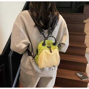 Detail of neon green and beige mini backpack with adjustable straps on a wooden staircase
