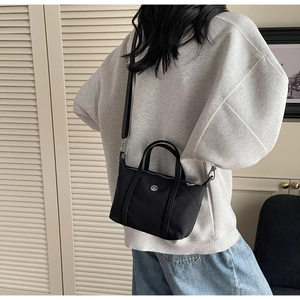 Rear view of model wearing a minimalist black canvas tote bag with adjustable strap