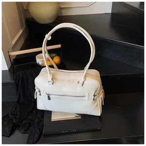 Detail of cream white Boston bag with silver zipper on dark wooden stairs background