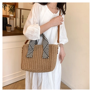 Détail du sac cabas en paille avec foulard à rayures noir et blanc sur l'anse
