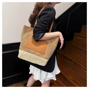Detail of handwoven straw tote bag with bicolor design and brown leather pocket on the front