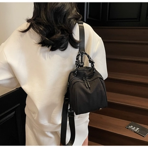 Close-up of lightweight black nylon mini backpack with textured woven handle and straps