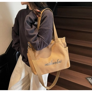 Detail of khaki canvas tote bag showing side pockets and the adjustable shoulder strap